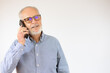 © Danko - Senior man having conversation talking on the phone over white background with a happy face standing and smiling with a confident smile