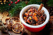 Christmas cooking concept with a bowl of homemade mincemeat for traditional mince pies with cinnamon sticks, anise, oranges and festive decorations at the background