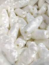 Lots Of White Polyester And Silk Threads. Sewing Machine Spools. Background On The Theme Of Light Industry