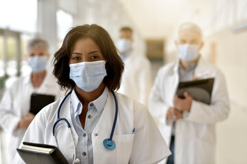 Wall Mural - Woman doctor standing in hospital, wearing face mask