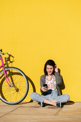 Wall Mural - young woman looking smart phone next to her bike