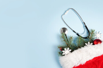 Medical stethoscope and christmas decorations in Santa Claus red bag on blue background. medical winter greeting card. Top view, flat lay, copy space