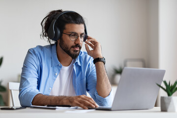 Wall Mural - Distance Learning. Western Man In Headphones Studying Online With Laptop At Home