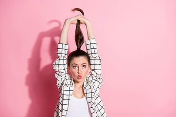 Sticker - Photo portrait of funny girl with plump lips pulling ponytail up isolated on pastel pink colored background