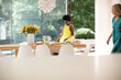 © Tom Merton/Caia Image - Mature woman in dress setting table for lunch in sunny dining room