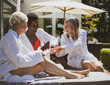 © Tom Merton/Caia Image - Senior women friends in spa bathrobes on sunny hotel patio