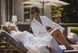 © Tom Merton/Caia Image - Happy senior women friends relaxing in spa robes on sunny hotel patio