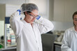 © Trevor Adeline/Caia Image - Female scientist putting on protective hair net in laboratory