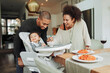 © Paul Bradbury/Caia Image - Happy parents feeding baby daughter at dining table