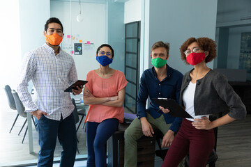 Wall Mural - Diverse group of work colleagues wearing masks in an office