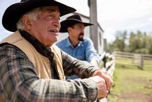 Senior Male Farmer In Cowboy Hat At Sunny Pasture Farm Fence