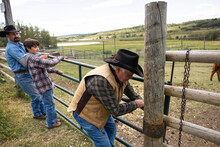 Multigenerational Male Ranchers Closing Pasture Gate On Ranch