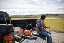 Boy Sitting In Pickup Truck With Tools On Sunny Rural Farm
