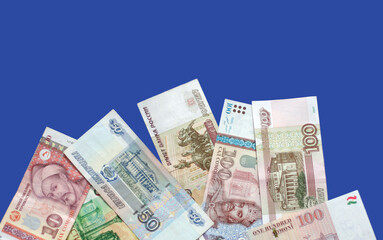 Photo of somoni bank notes from Tajikistan and Russian ruble bank notes on blue background. 