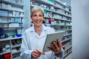 Wall Mural - Caucasian senior pharmacist scrolling on digital tablet smiling standing in pharmacy