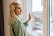 © Angelov - Happy young woman stand near window breathe fresh air stretch exercise in bedroom, smiling millennial girl overjoyed welcome new sunny morning at home or hotel, optimism, happiness concept