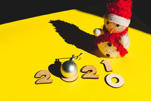 Wooden Numbers 2021 Chainging 2020, Little Cute Snowman And A Silver Christmas Ball On A Yellow Background. Minimal New Year Concept.