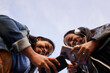 © CarlosBarquero - Low angle of two young African American women with headphones listening to music with mobil outdoors. Isolated silhouette in the sky. Copy space