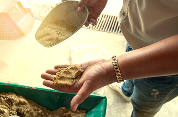 A man's hand wearing a gold bracelet shows the fine sand that was scooped from the box.