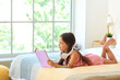 Cute little girl with headphones reading in bedroom