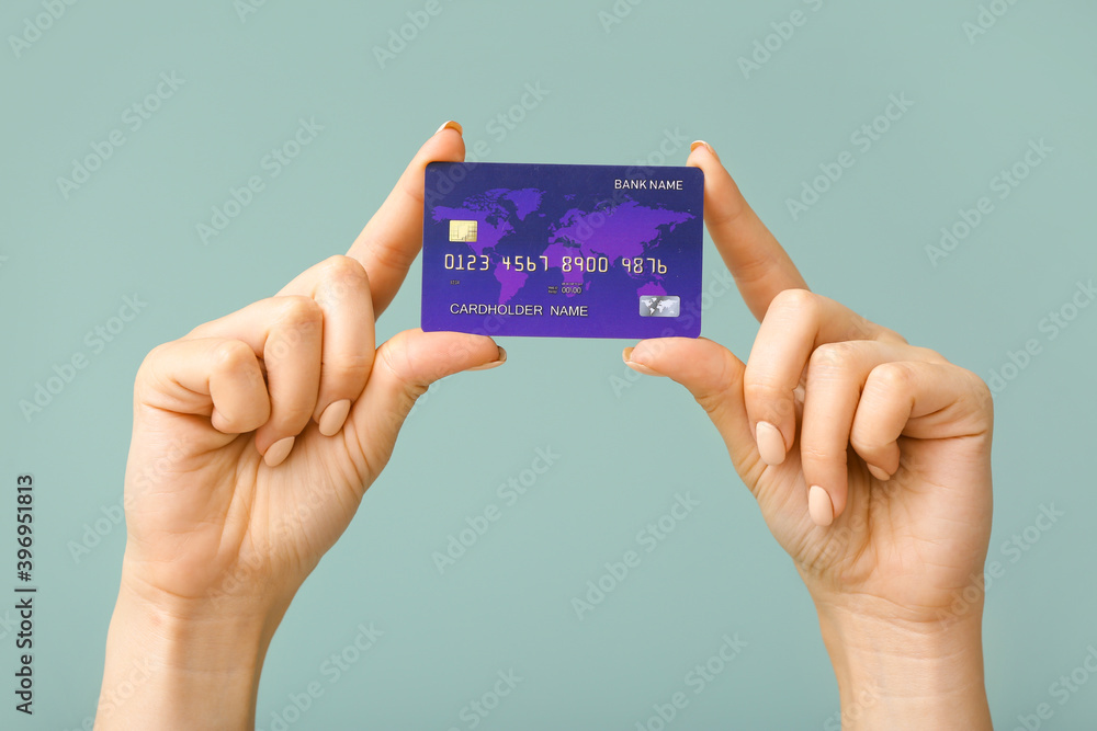 Female hands with credit card on color background