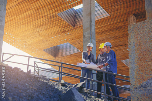 Fotografie, Obraz Structural engineer and architect working with blueprints discuss at the stairway, outdoors building construction site