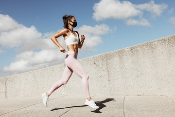 Wall Mural - Sports woman wearing face mask running outdoors