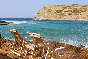 Two deckchairs facing the sea symbolize tranquility, in Greece