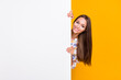 Photo portrait of funny girl hiding behind white wall with blank space isolated on vivid yellow colored background