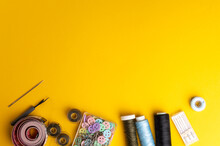 Workspace With Creative Accessories: Scissors, Office Knife, Sewing Thread And Other Sewing Accessories On A Orange Background