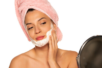 Young beautiful woman applying shaving foam on her face