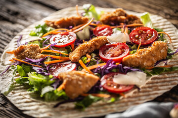 Wall Mural - Open tortilla with chicken nuggets, chery tomatoes, red cabbage, salad, carrot stripes and parmesan shavings