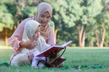 Muslim mother teaches her daughter to read the Quran at the park, islamic people