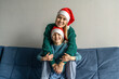 © Татьяна Максимова - Cute little girl and her beautiful mother in Santa hats are looking at camera and having fun on sofa.
