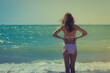 © Postmodern Studio - Skinny girl in a swimsuit, the view from the back, stands by the sea and prepares to swim. Water background and copy space