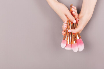 Wall Mural - Manicure and nail care concept. Minimal composition of the woman hands on the grey background. Classic pink nail polish. Flat lay, top view.