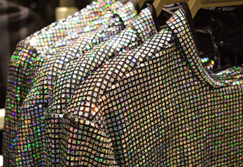 Lots of colorful rainbow sequins on dresses on hangers in the store. Trendy festive clothes for New Year and Christmas.