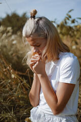 Wall Mural - A teenage girl closed her eyes while praying in a field. Hands folded in prayer faith, spirituality and religion concept