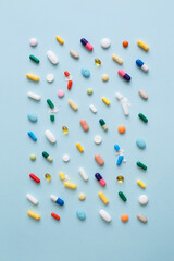 Wall Mural - Creative layout of colorful pills and capsules on blue background. Minimal medical concept. Pharmaceutical, Covid-19 or Coronavirus. Flat lay, top view