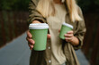 © Iuliia Pilipeichenko - Green paper cup with coffee in woman hand. Time for drink coffee in city. Coffee to go. Enjoy moment, take a break. Disposable paper cup closeup. Delicious hot beverage. Blank space for text, mockup