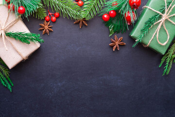 Top view above of Christmas holiday background. Composition with fir pine branches, green gift kraft box decorations on black background. Winter, Christmas, new year concept. Flat lay, copy space.