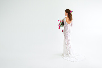 joyful girl bride in a white knitted dress posing with a bouquet of flowers