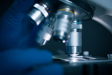 Wall Mural - close-up shot of sample slide and microscope with metal lens at laboratory.