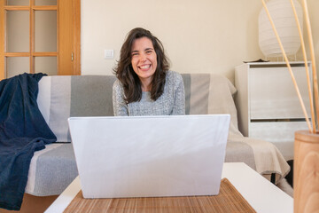 A  portrait of a young and smiling caucasian woman using her laptop at home