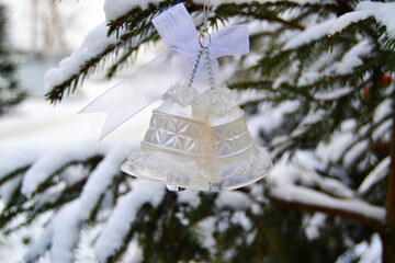 White crystal bells on the Christmas tree in the snow in winter