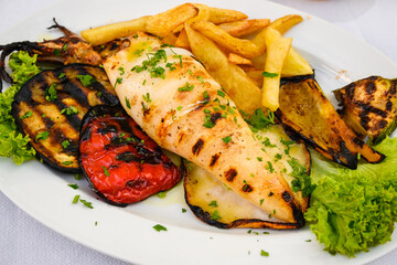 Wall Mural - Grilled squid served with vegetables and fries. Traditional Greek dish.