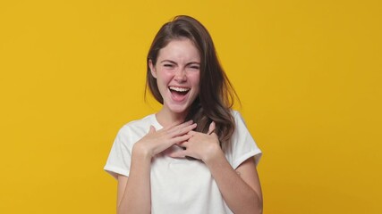 Wall Mural - excited laughing brunette young woman 20s years old in white t-shirt posing isolated on yellow color