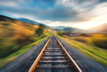Railroad In Mountains With Motion Blur Effect At Sunset In Autumn. Industrial Landscape With Railway Station And Blurred Background With Sky, Trees, Grass. Railway Platform In Speed Motion, Concept