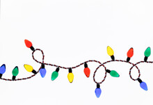 Original Christmas Photograph Of A String Of Bright Red, Green, Yellow And Blue Christmas Lights Looped Across A Bright White Background.