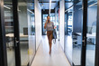 © Wavebreak Media - Smiling african american woman walking talking on smartphone in office